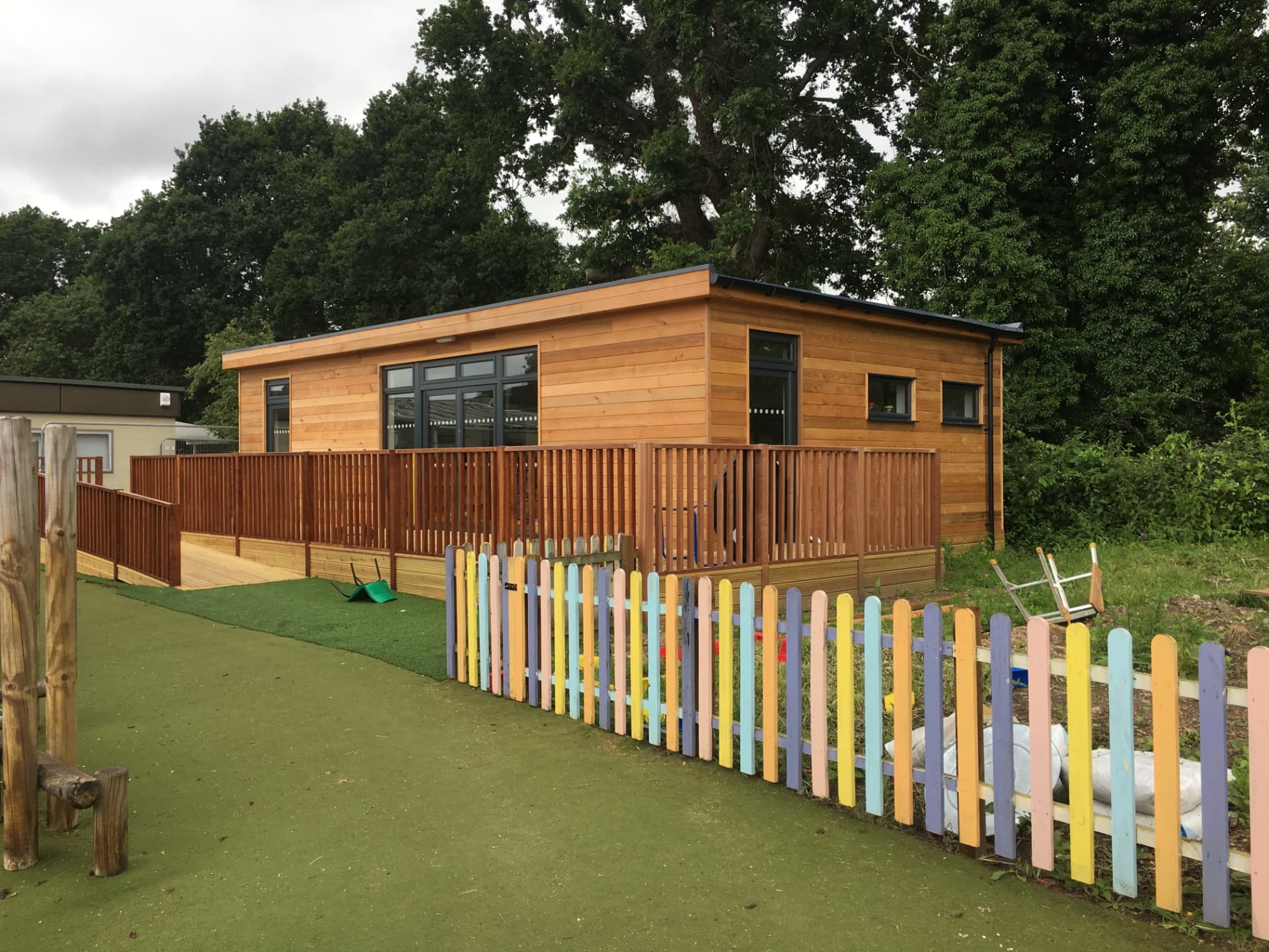 Timber-clad nursery building with colourful picket fence